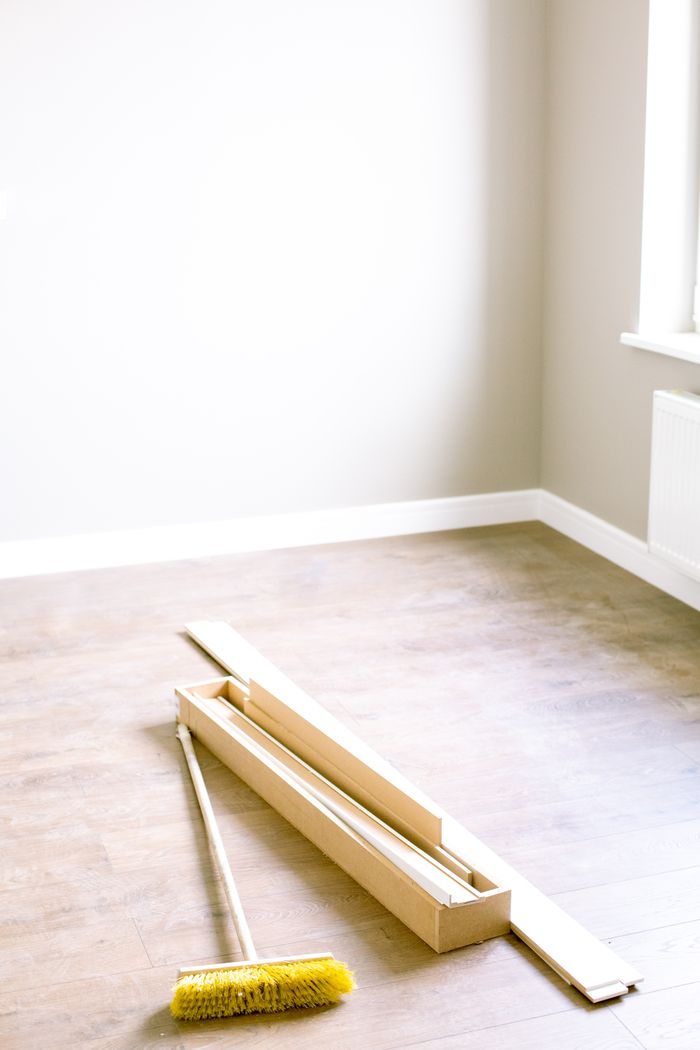 Une pièce vide avec des planches en bois et un balai, prête pour une rénovation.